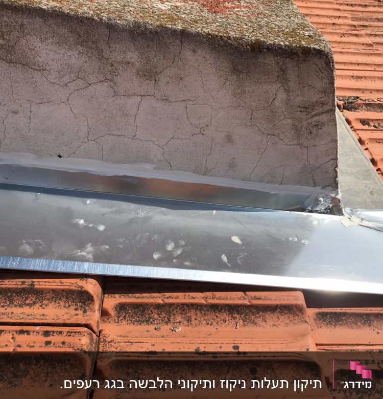 גג רעפים עם יריעת מתכת ליד קיר בטון